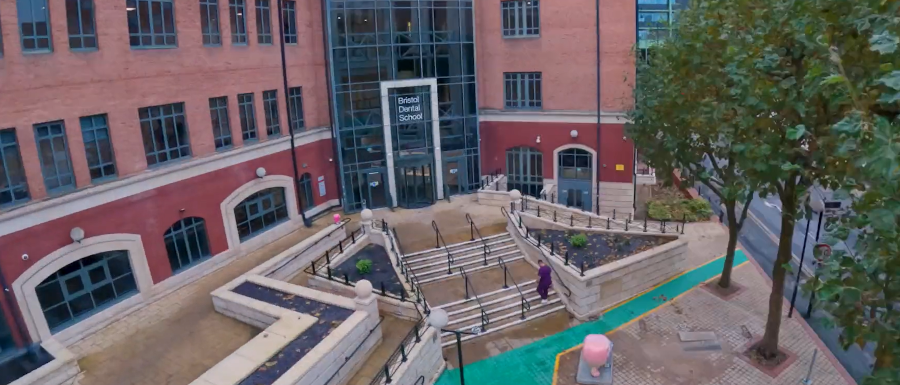 A view of the outside of the new Bristol Dental School building on Temple Quay, showing the main entrance, access paths and planting.